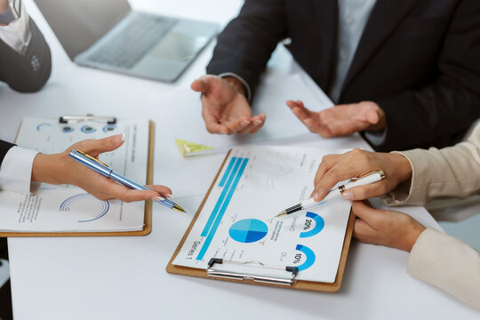 Business people analyzing financial data charts and graphs during a corporate meeting in an office setting