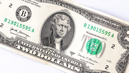 A detailed close-up image of multiple two-dollar bills featuring the portrait of Thomas Jefferson, arranged in an overlapping manner. Two american dollars banknote close up.
