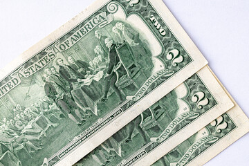 A detailed close-up image of multiple two-dollar bills featuring the portrait of Thomas Jefferson, arranged in an overlapping manner. Two american dollars banknote close up.