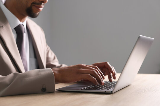 African-american man using laptop at wooden table indoors, closeup