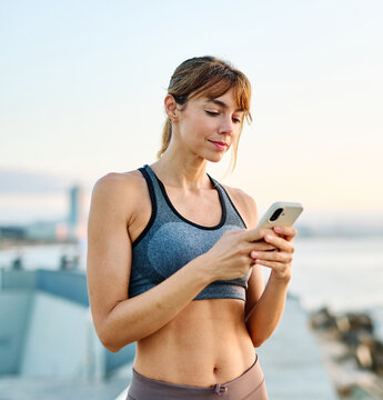 Woman in sportswear checks phone while enjoying outdoor fitness activity