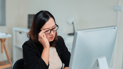 Businesswoman experiencing eye strain and fatigue, rubbing her tired eyes while working long hours in an office environment