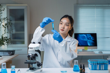 Young female scientist performing chemical experiment with blue liquid in test tube, developing new...