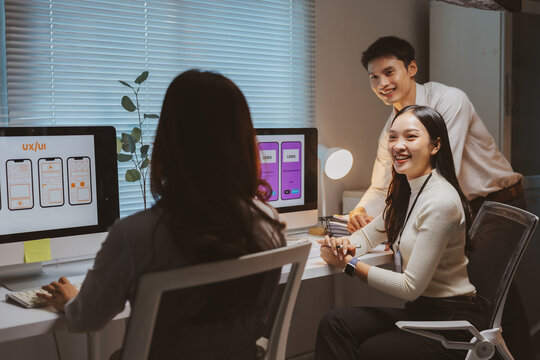 Asian UIUX designers and developers collaborating on a new mobile application interface, working together on a late night project - Powered by Adobe