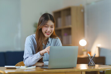 Young asian woman smiling while on a video call at her desk, working remotely or studying online from home