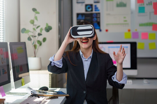 Woman playing or working in virtual reality headset in office. Exploring metaverse or future technology concept
