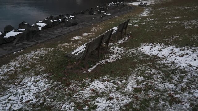 薄っすらと雪が被った湖畔の公園ベンチ