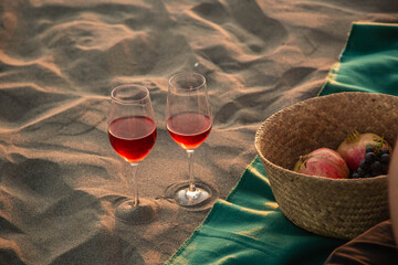 two glasses of red wine and fruits on the sand beach