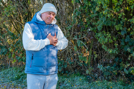 senior man stops during winter run holding chest, heart discomfort, jogging, running challenge, health awareness, exercise caution, unexpected pause outdoors, outdoor fitness, active lifestyle