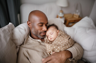 El vínculo se basa en el silencio: gesto protector, ambiente cálido y pausa emocional compartida. Adulto con bebé dormido en una silla gris, vista aérea, entorno familiar, imagen íntima y serena.