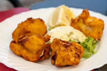 Dish with pieces of breaded and fried fish from the Canary Islands in a restaurant in Tebnerife, accompanied with tartar sauce and lemon