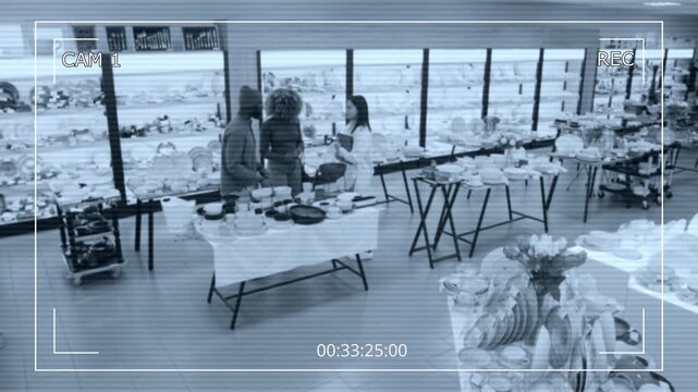 Wide CCTV surveillance camera overhead shot of young female saleswoman with tablet walking over to serve African American couple shopping in kitchenware store, helping and consulting on merchandise