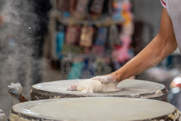 Close-up of the intricate technique of making Moroccan warqa pastry, as the dough is tapped and stretched into translucent layers over a hot surface. Skillful bastilla maker making bastilla sheets. 