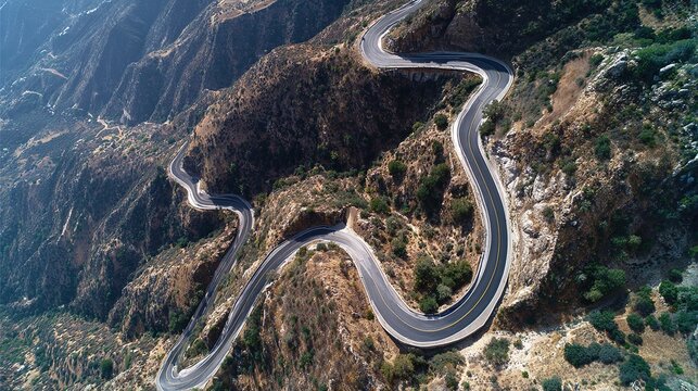 Aerial drone view of a dangerous winding mountain road switchbacks carving through arid rocky landscape