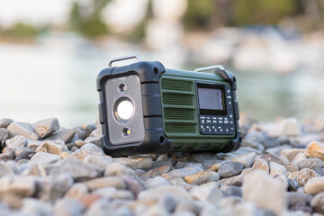 Rugged Green Portable Radio on Pebble Beach by Water’s Edge – Outdoor Survival Gear