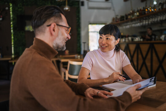 Diverse business partners discussing work in restaurant meeting