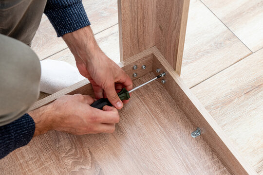 Man handyman furniture assembler assemble table with hand screwdriver and screws