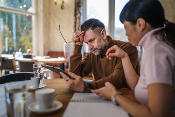 Concerned business colleagues looking at tablet during meeting