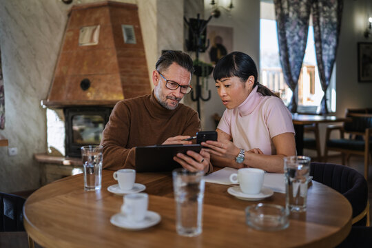 Diverse business partners collaborating digitally in vintage style cafe