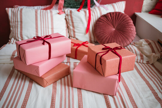 Close-up of a stack of wrapped Christmas gifts on a bed decorated with a festive wreath