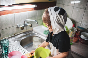 A little girl washing dishes