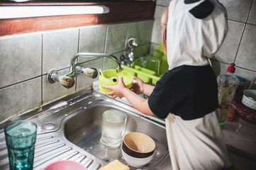 A little girl washing dishes