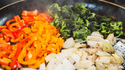 Colorful mix of onions, broccoli, and bell peppers sizzling in a pan. Fresh vegetables, perfectly...