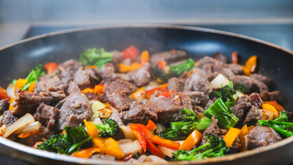 Beef strips sizzling with broccoli, bell peppers, and onions in a dry fry. Golden brown, juicy, and perfectly cooked for a healthy meal.