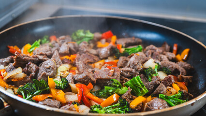 Beef strips sizzling with broccoli, bell peppers, and onions in a dry fry. Golden brown, juicy, and perfectly cooked for a healthy meal.