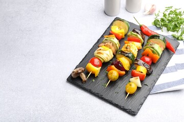 Skewers with tasty grilled vegetables on light table, closeup. Space for text