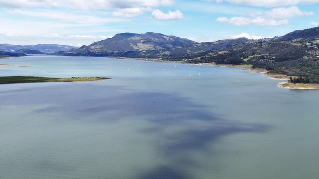 Gran plano general de la Laguna de Tomin&eacute; en Cundinamarca - Colombia, donde se muestra las monta&ntilde;as y paisajes naturales que rodean la laguna y los veleros que navegan en ella.