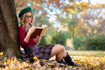 A beautiful woman reading a book in an autumn park