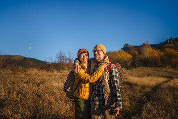 Happy active senior couple embracing outdoors during autumn hike