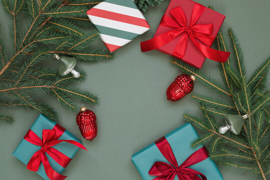 Overhead view of  wrapped gift boxes, festive Christmas baubles and fir branches on a green background