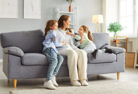 Mother, son, and daughter laughing, sharing an embrace and engaged in conversation on a couch at home. Enjoying leisure time together filled with love, family bonding, and joyful moments.