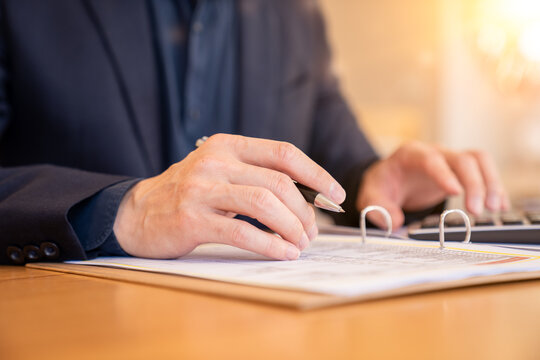 Businessman reviewing audit documents with calculator and financial file folders.Audit and taxes in business.