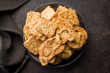 Crunchy salted crackers on plate on black table. Top view.