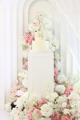 Baby celebration cake on a pedestal surrounded by lush florals. Concept: premium event setup for baby shower or christening. Perfect for event planners, decorators, cake artists, and marketing . 