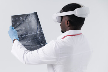 AI Assistant technology for medicine. African male adult doctor examining MRI scan with vr headset in modern healthcare setting