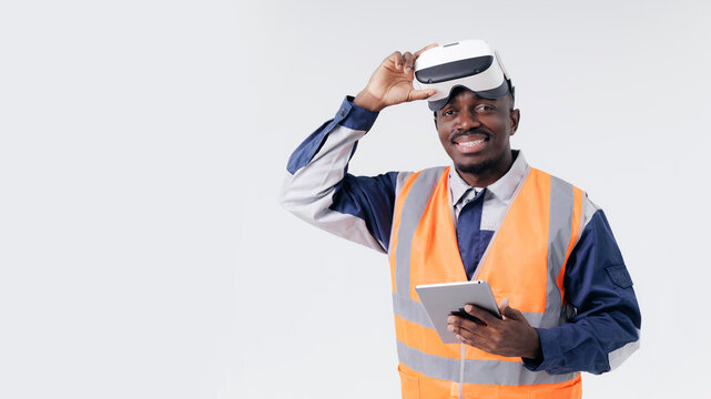 Portrait happy American African adult male construction industry worker using vr headset with tablet on white background