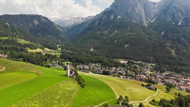 St. Valentin church surrounded by meadows and fields, with Schlern massif in background, Castelrotto in Dolomites Alps. South Tyrol, Italy