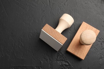 Two wooden stamps on dark textured table, top view. Space for text