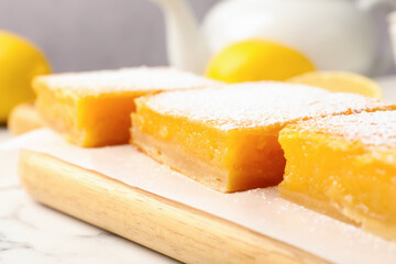 Tasty lemon bars with powdered sugar on white marble table, closeup