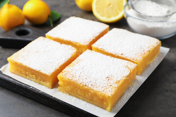Tasty lemon bars with powdered sugar on grey table, closeup
