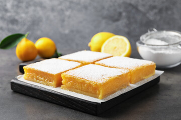 Tasty lemon bars with powdered sugar on grey table, closeup