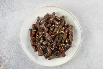 Stir-fried teriyaki beef with sesame seeds on a gray background. Top view. Asian cuisine.