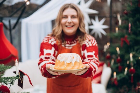 Lemon, vanilla marble bund cake in woman hands. Happy 30s girl standing near decorated Christmas tree. Winter time and holidays. Celebration banner,