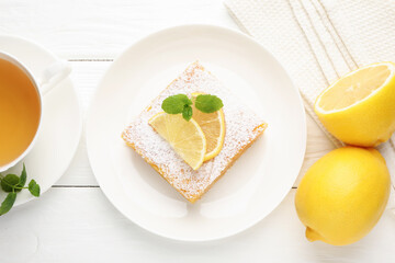 Tasty lemon bar with powdered sugar and mint served on white wooden table, flat lay