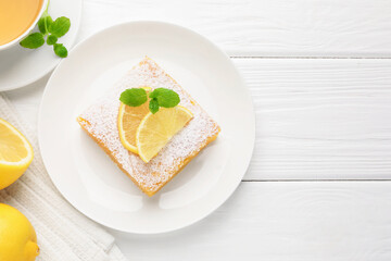 Tasty lemon bar with powdered sugar and mint served on white wooden table, flat lay. Space for text