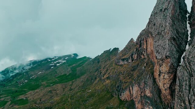 Aerial drone shot of Jagged cliff edge of Seceda mountain in Dolomites. Jagged ridges in foggy cloudy day